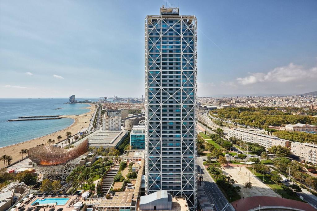 A steel exoskeleton standing outside the glass wall of a seafront tower - Hotel Arts Barcelona, Barcelona, Spain