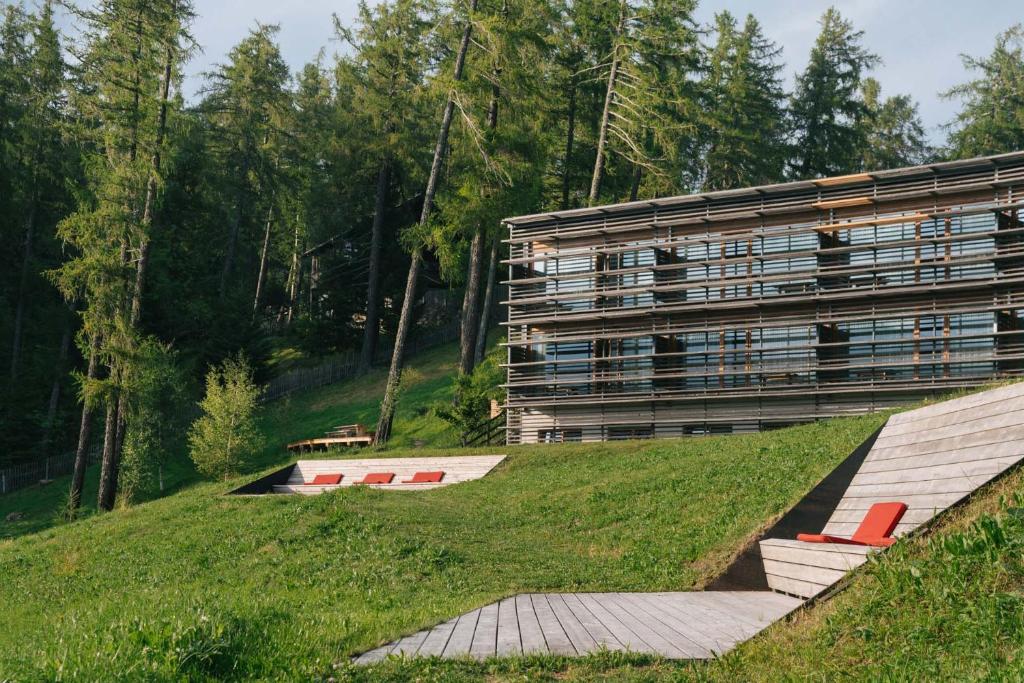 A long timber building lying along a wooded mountain ridge - Vigilius Mountain Resort, Lana, South Tyrol, Italy