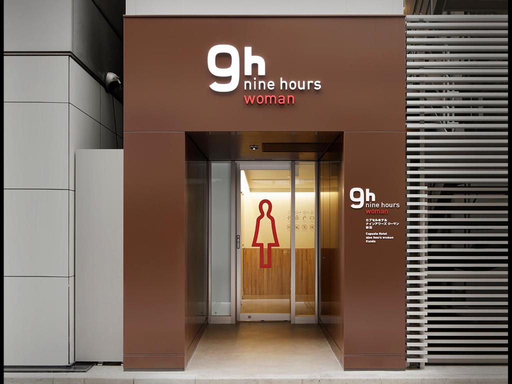 Two tiers of capsule openings along a lit interior corridor - 9h nine hours Kanda, Tokyo, Japan