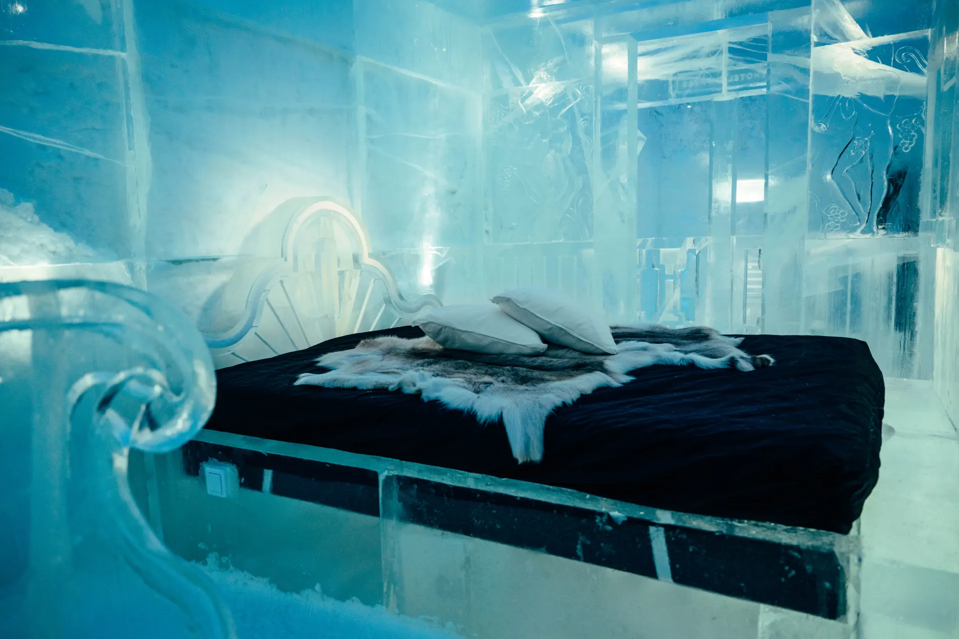 A carved wall of packed snow lit from inside a winter building